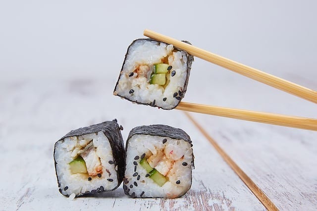 holding a sushi using wooden chopsticks