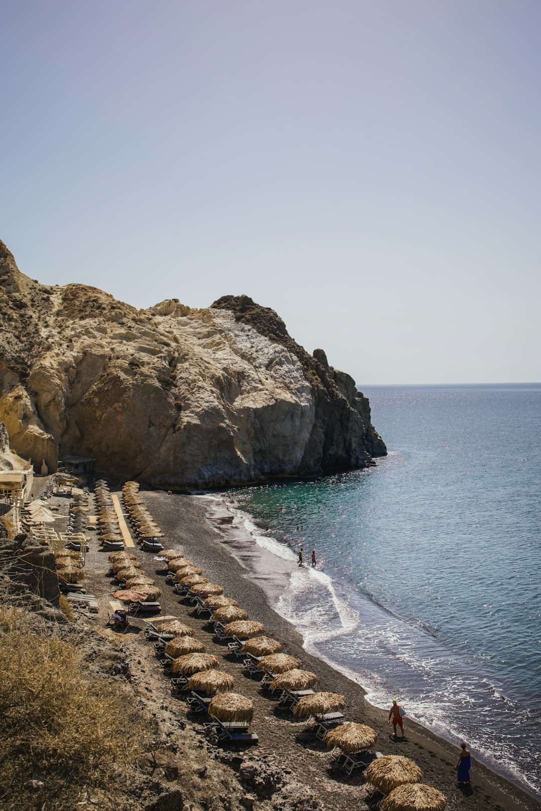 A sandy beach next to a rocky cliff
